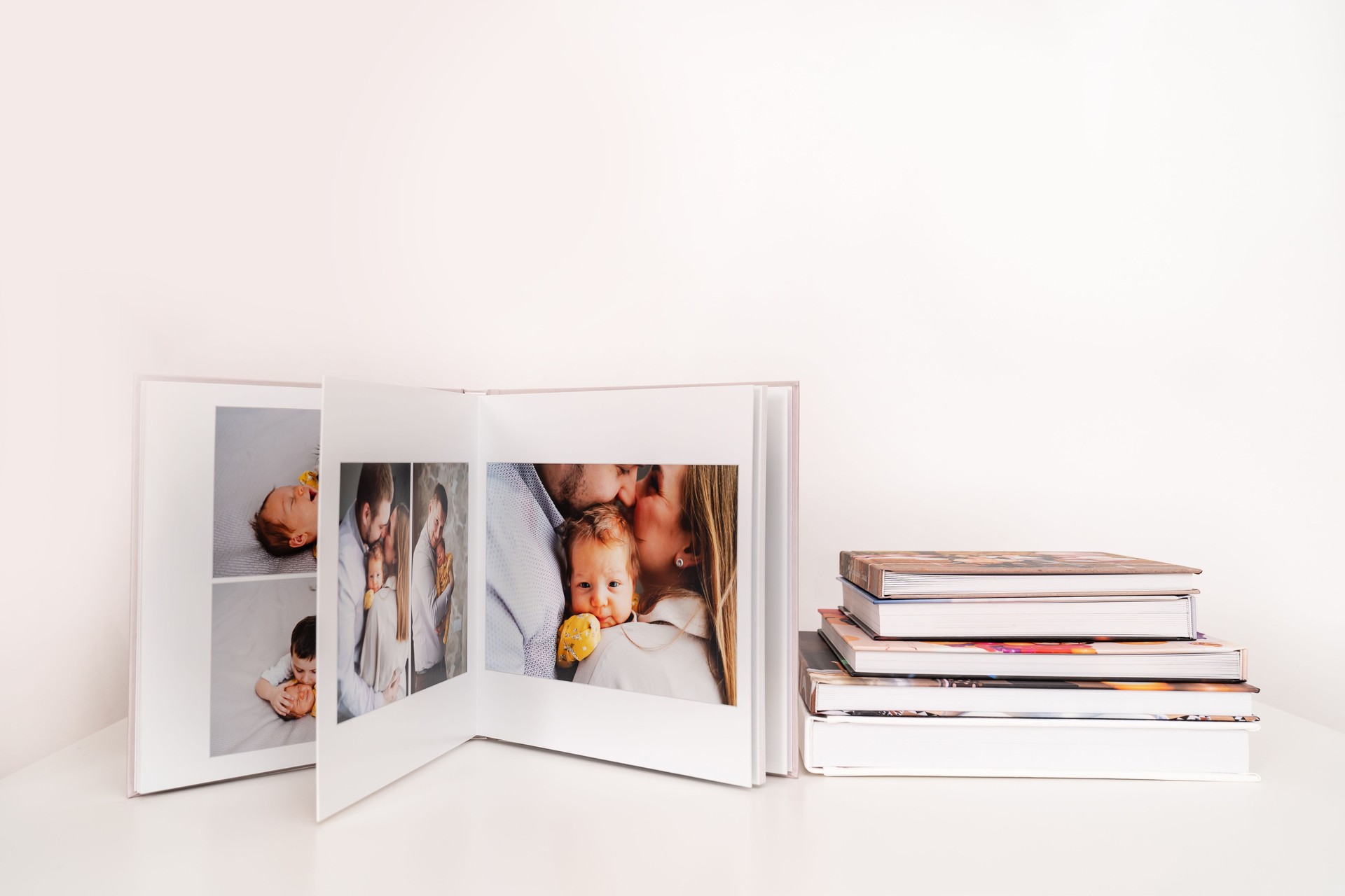 on white table open photobook from photo shoot of family with newborn.